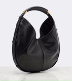 A black leather hobo shoulder bag with gold-tone hardware, displayed on a light gray background with a white marble surface.